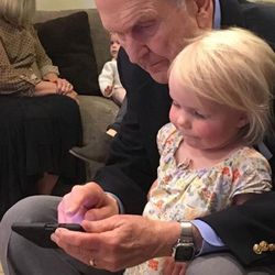 President Russell M. Nelson shows his phone to a great-granddaughter.