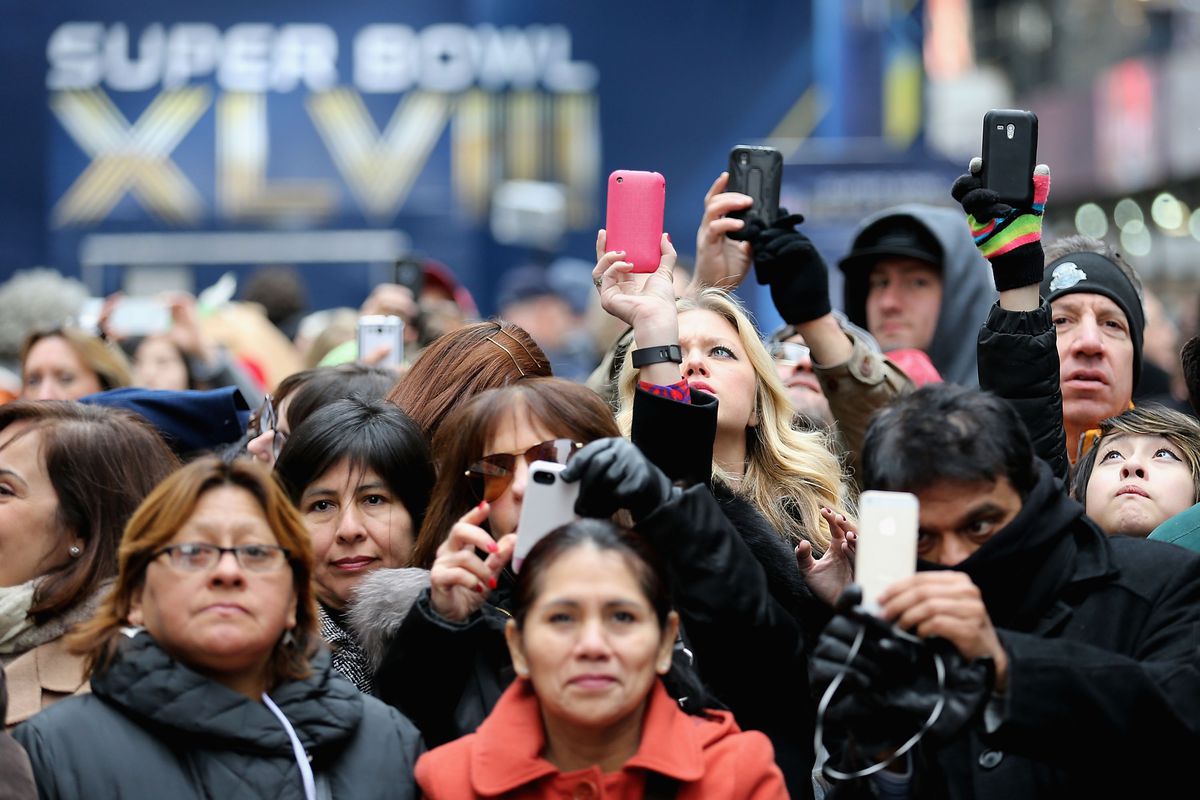 Onlookers take photos while walking through Times Square Friday