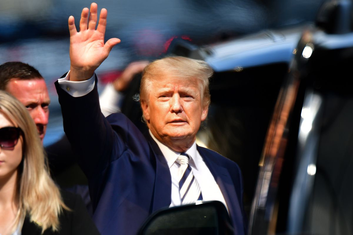 Donald Trump waves as he gets into a car.