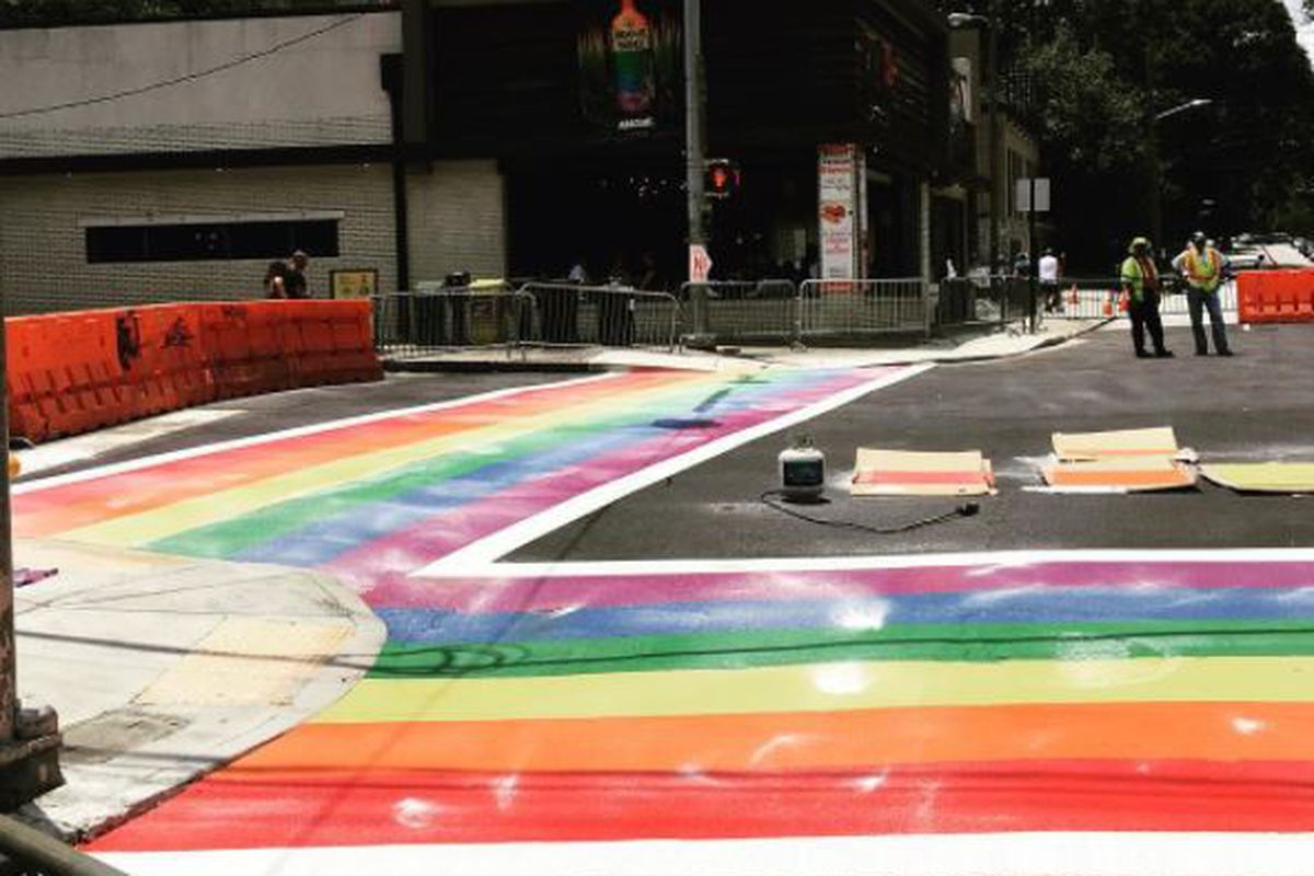 Work progressing on painting the rainbow crosswalk.