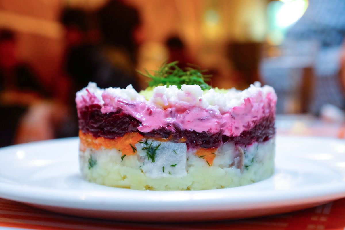 A plate of Herring Under a Fur Coat at Kachka, layered with beets, potatoes, herring, and other components.