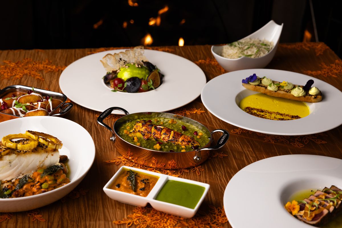 A low-angle shot of modern, fine dining Indian food in silver serving trays including fish and lobster with bright green sauce at new Orange County restaurant Kahani.