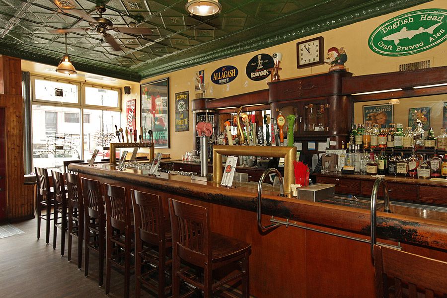 A wooden bar with backed stools and several beer taps.