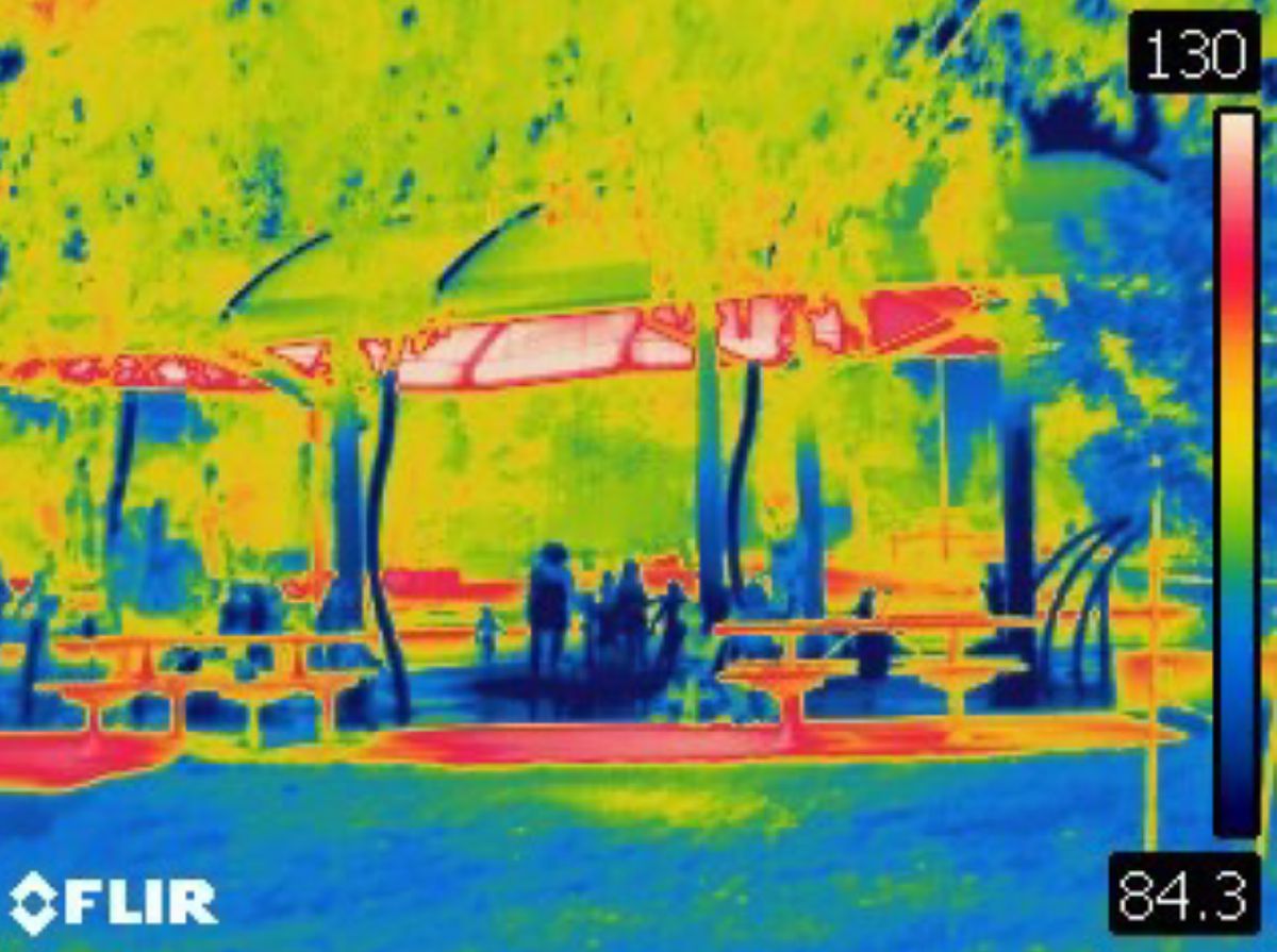 An infrared image of the splash park and picnic tables. The unshaded tables are red, while the ares in the shade are blue.