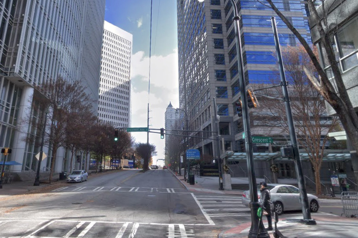 A photo of an atlanta intersection with tall glassy buildings and very few cars. 