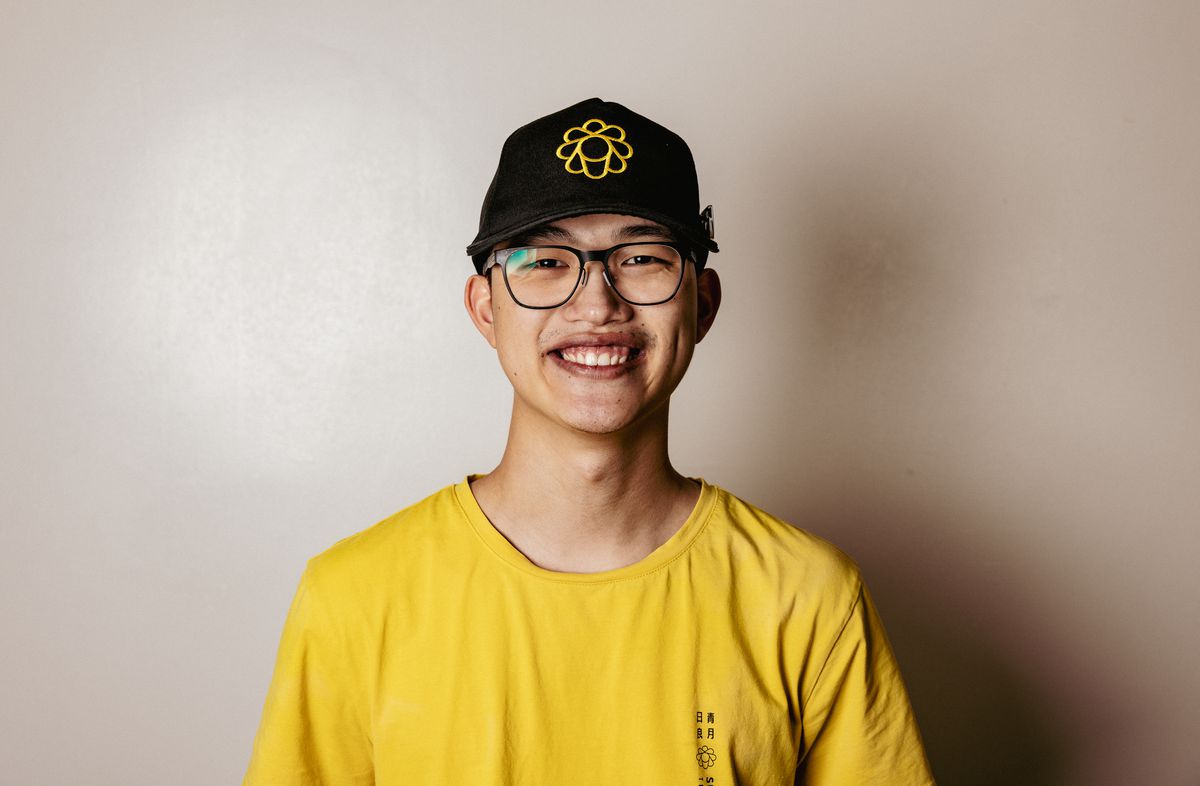 A man in glasses and a boba tea baseball hat smiles at the camera.