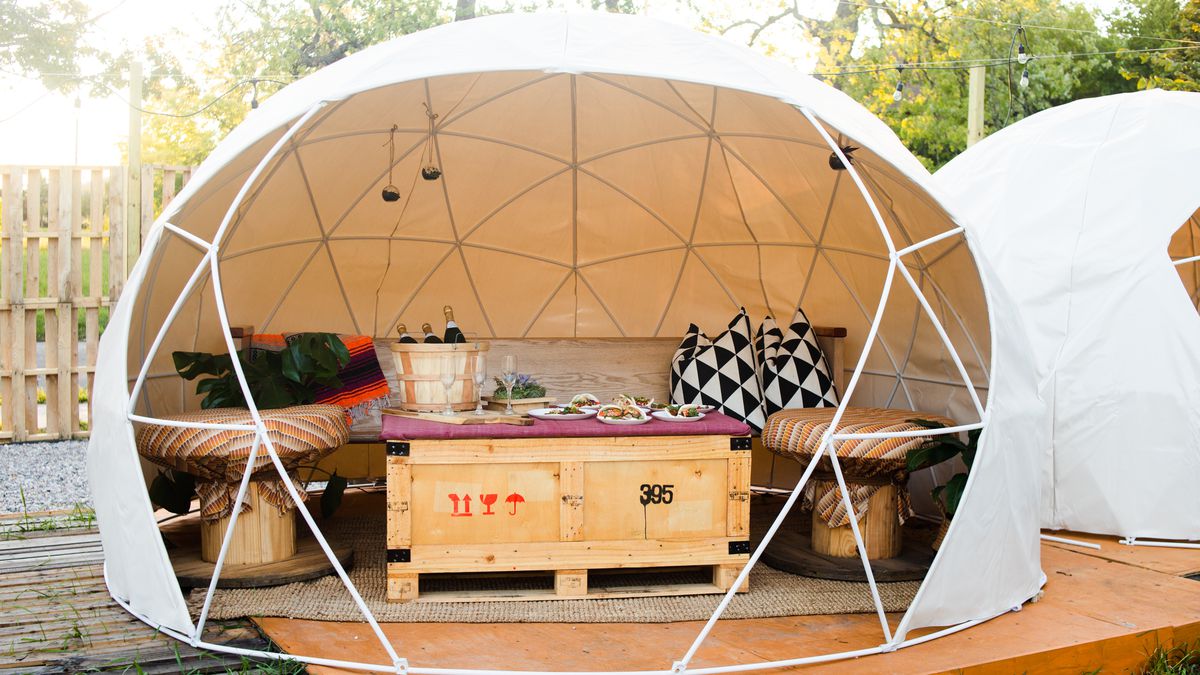 A geodesic dome is open on one side revealing furniture at East Eats.