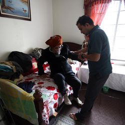 Tom Neupane helps his grandfather, Bhagi Neupane, to sit up at home in Salt Lake City on Friday, Nov. 6, 2015. Bhagi suffers from asthma and requires oxygen most hours of the day.
