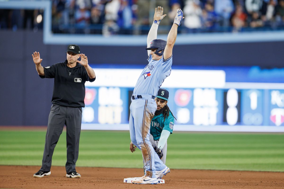 Matt Chapman of the Toronto Blue Jays celebrates on base in front of J.P. Crawford #3 of the Seattle Mariners as he hits a double in the seventh inning of their MLB game at Rogers Centre on April 29, 2023 in Toronto, Canada.