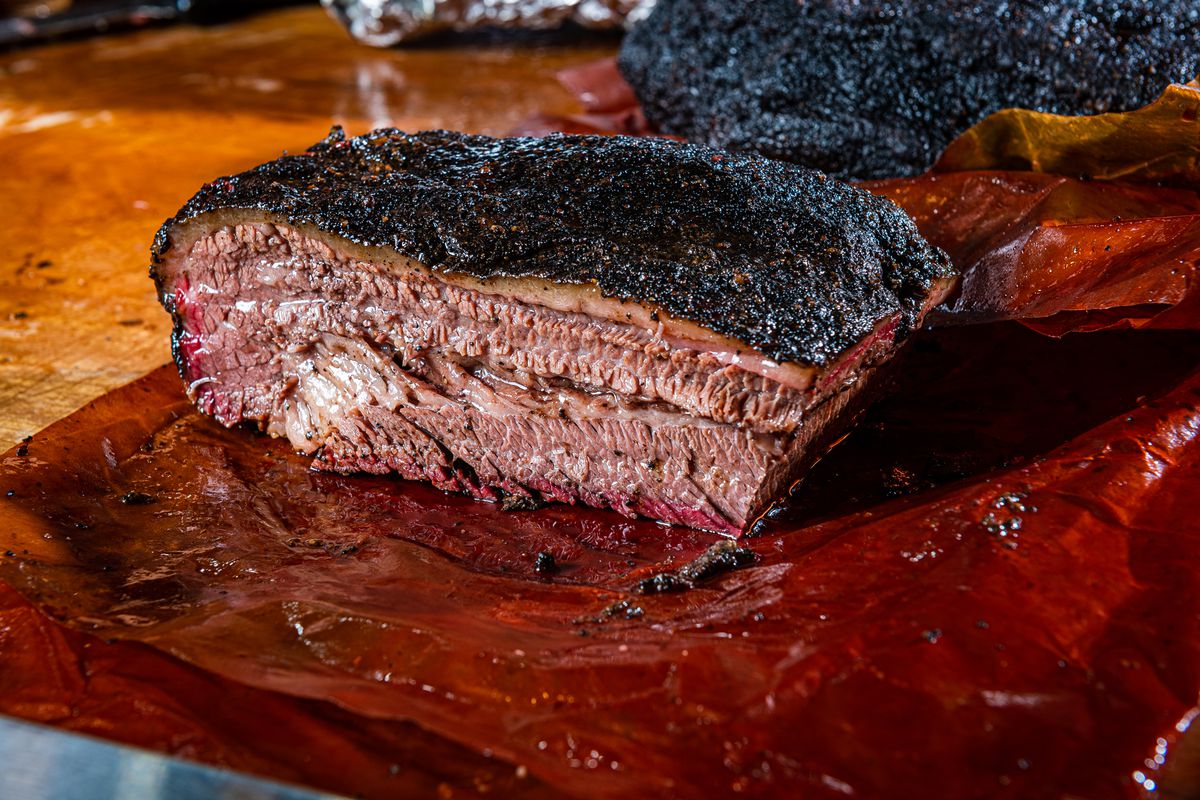 A slab of 2Fifty’s cooked brisket is sliced in half to reveal a juicy center.
