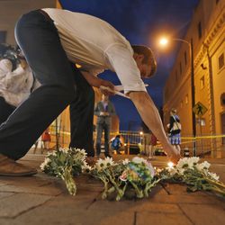 Charlottesville resident Elliot Harding lights a candle as he places flowers and a stuffed animal at a makeshift memorial for the victims after a car plowed into a crowd of people peacefully protesting a white nationalist rally earlier in the day in Charlottesville, Va., Saturday, Aug. 12, 2017. (AP Photo/Steve Helber)