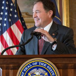 Utah Gov. Gary Herbert laughs as he makes an opening statement prior to signing HB127, which adds the "In God We Trust" license plate to the standard options available, at the Capitol in Salt Lake City on Monday, March 21, 2016.