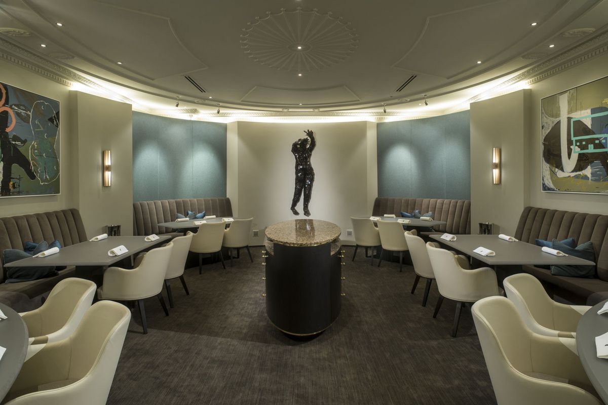 One of Alinea’s dining areas is modern with light off-whites and a central statue.