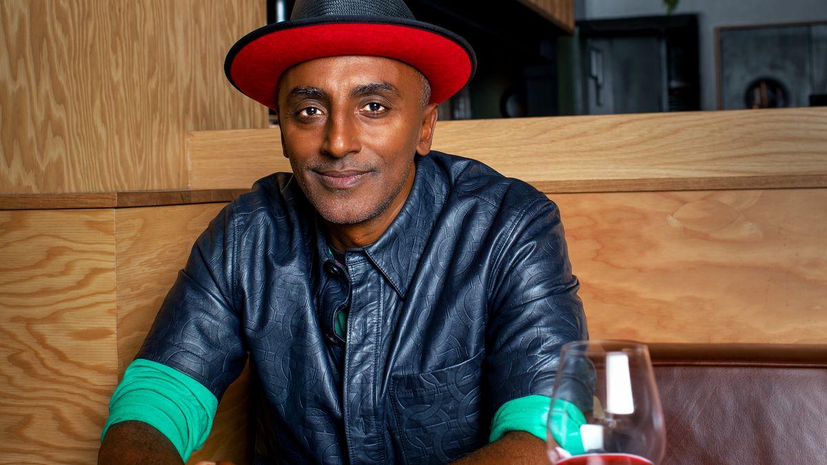Chef Marcus Samuelsson sits at a table in a hat.