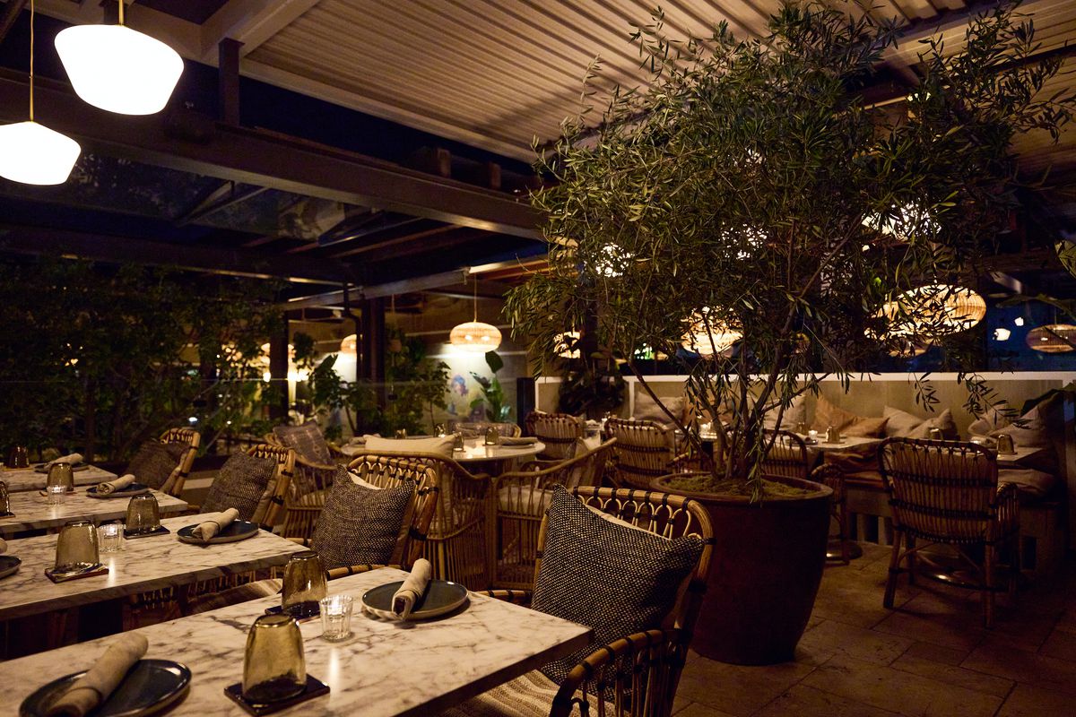 Rooftop dining room with tables, chairs, and lots of plants at Mírate in Los Angeles, California.