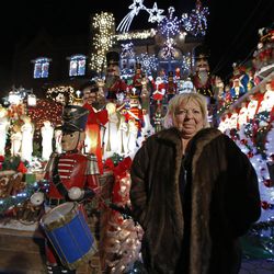 In this Dec. 14, 2016, photo, Dyker Heights resident Lucy Spata, whose elaborate Christmas decorations along with those of her neighbors, draw thousands of onlookers to the Brooklyn Borough neighborhood each holiday season, stands in front of her home in New York. In spite of the inconveniences, Spata says she still loves how people flock in droves to see the brilliant, over-the-top spectacle each holiday season. 