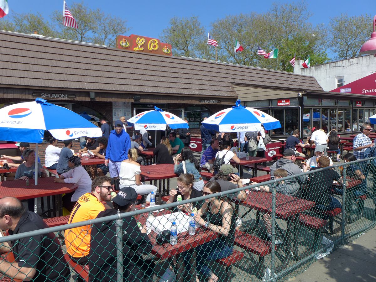 An outdoor seating area with picnic tables and umbrellas at L&amp;B Spumoni Gardens in Gravesend, Brooklyn.