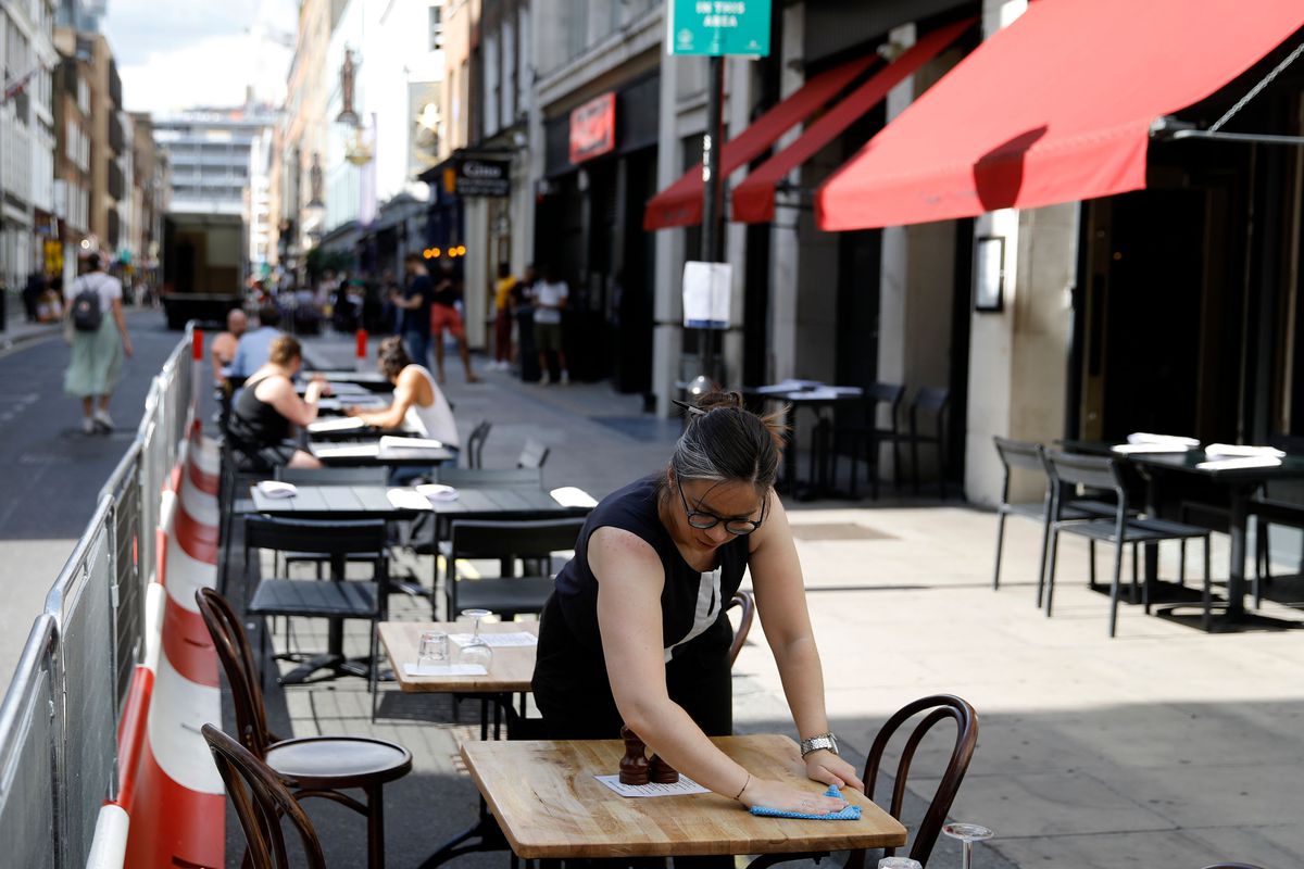 A restaurant worker cleans a table outside a London restaurant in the Eat Out to Help Out coronavirus discount scheme