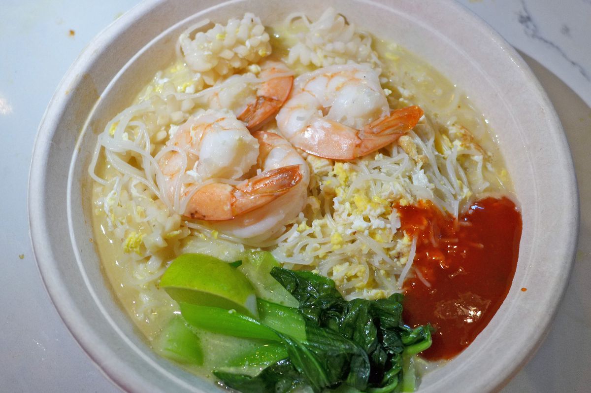 A bowl of noodles with squid and shrimp on top.