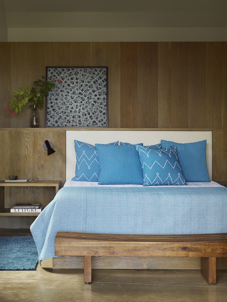 Room with wooden walls and floors, and a bed with blue bedding.