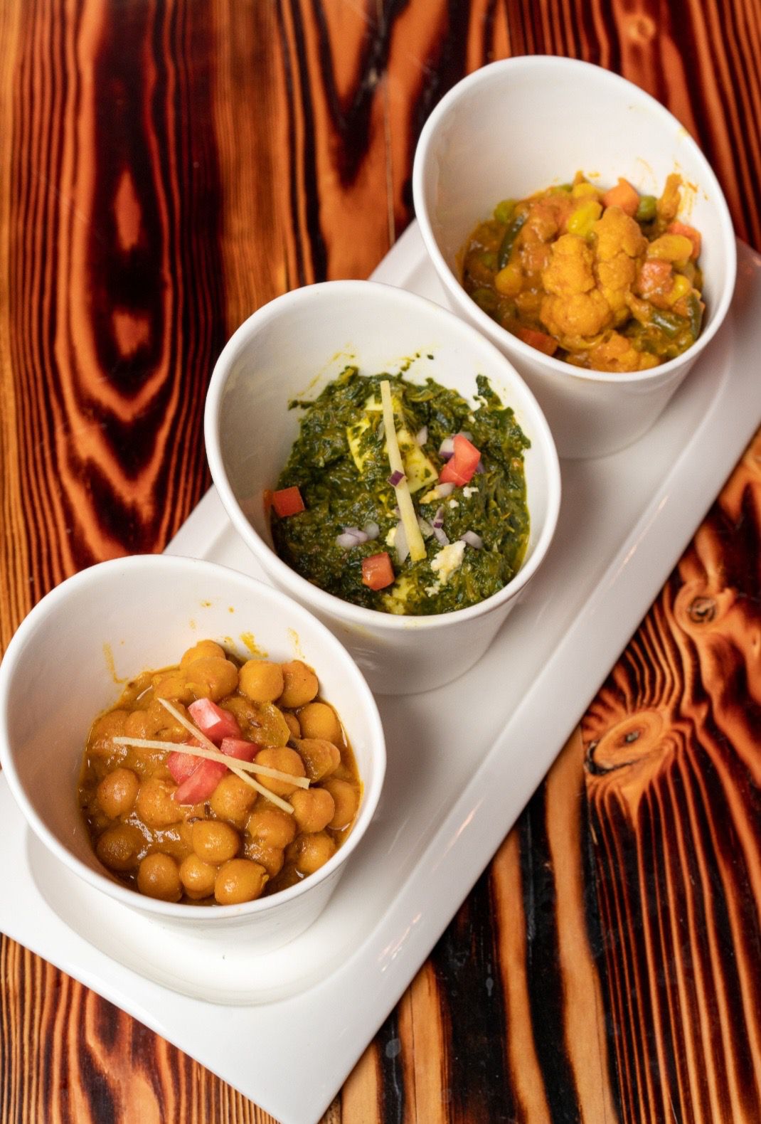 A trio of curries lined up in a row in white bowls