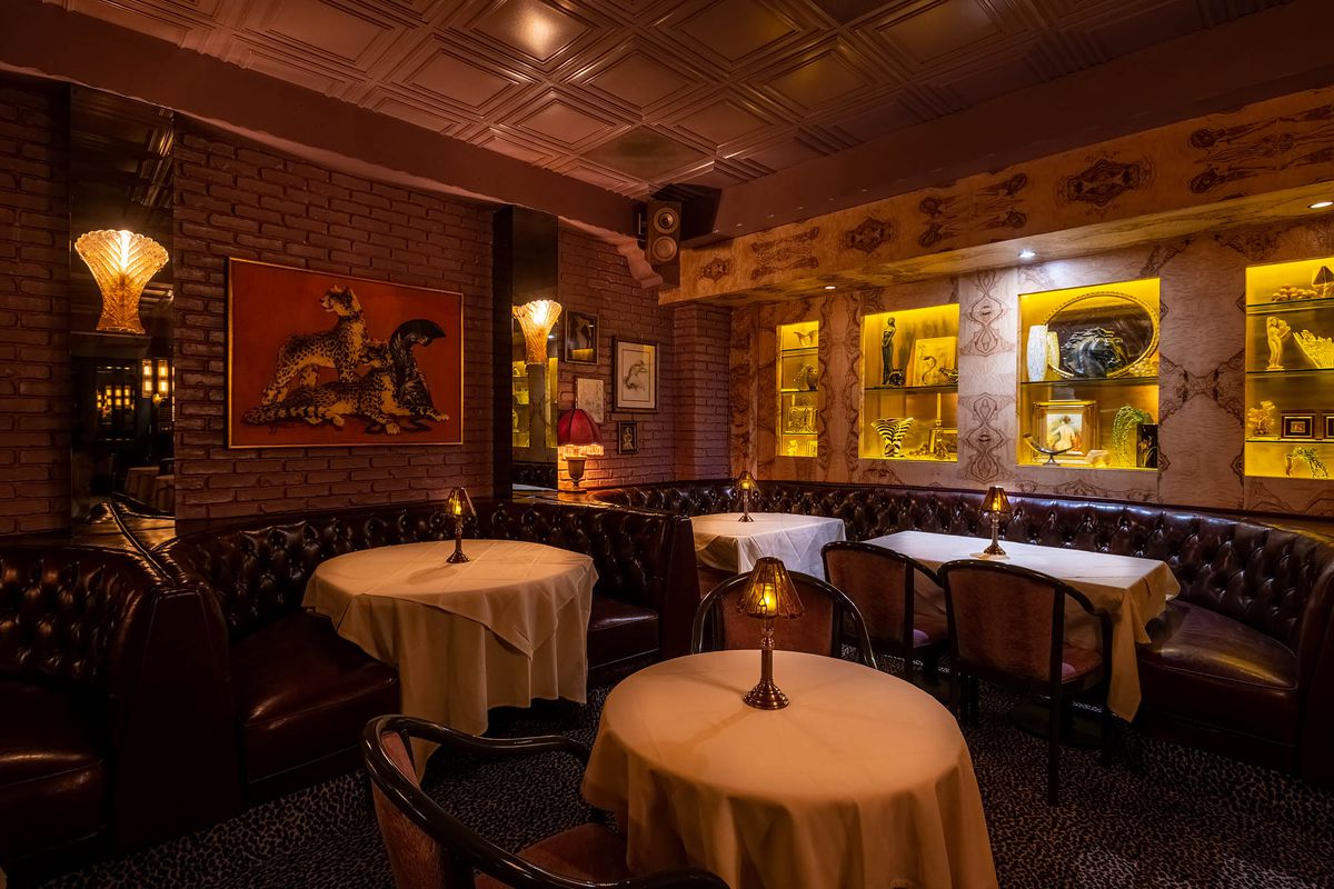 A corner location of a dimly lit Italian restaurant with white tablecloths.