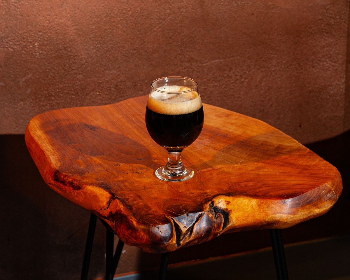 A tulip glass of stout on a wooden table.