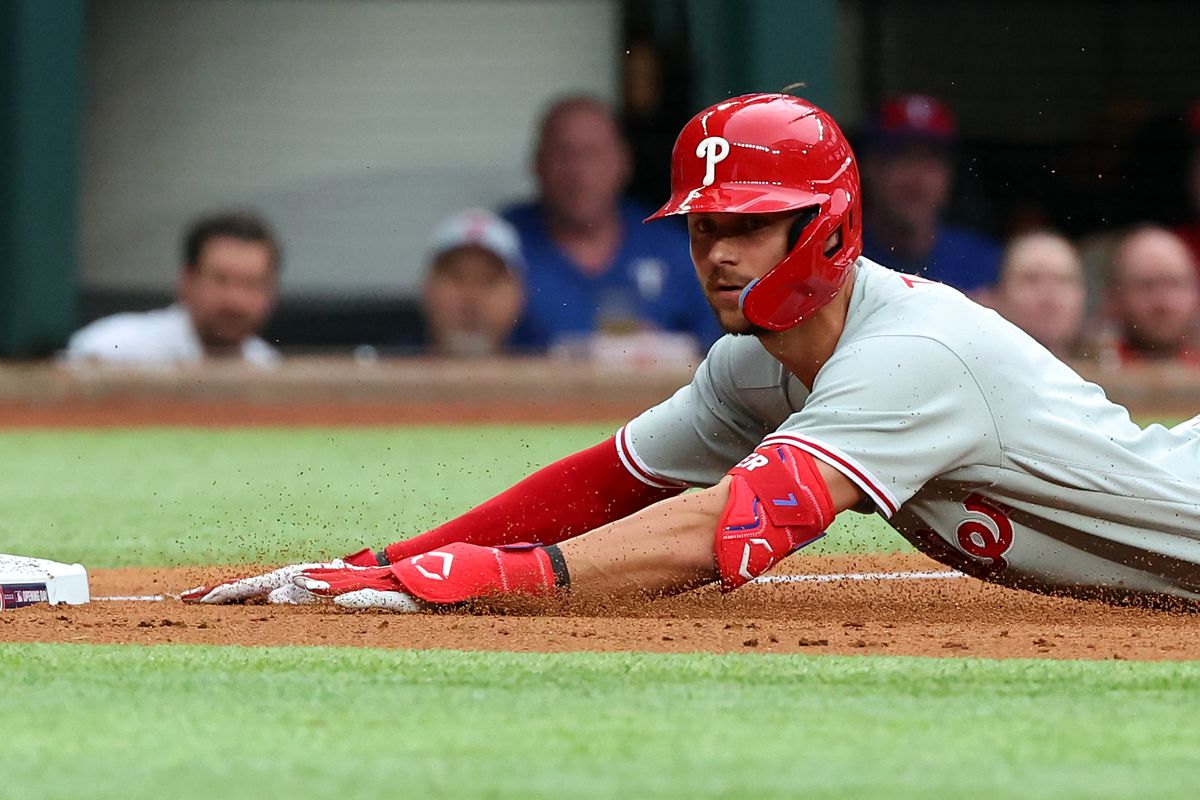 Trea Turner of the Philadelphia Phillies slides into third base on a triple in the third inning against the Texas Rangers on Opening Day at Globe Life Field on March 30, 2023 in Arlington, Texas.