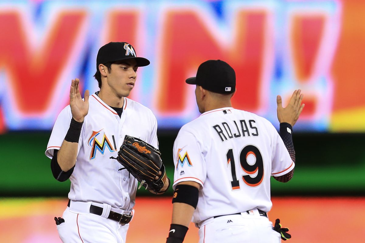 Christian Yelich #21 of the Miami Marlins slaps hands with Miguel Rojas #19 after the game against the Arizona Diamondbacks at Marlins Park