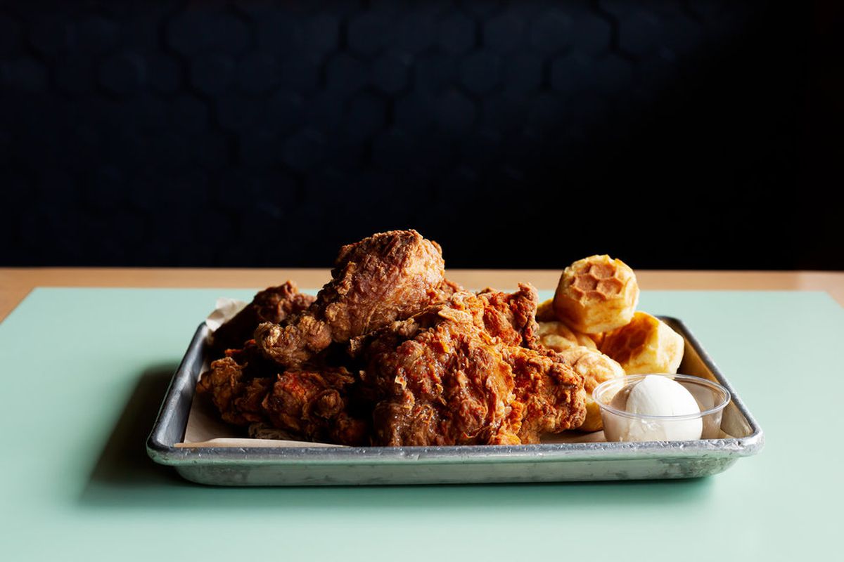 A tray of fried chicken with corn muffins and honey butter.