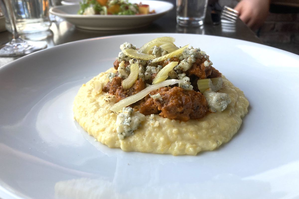 A piles of fried chicken livers sits on a bed of polenta with pickled celery.