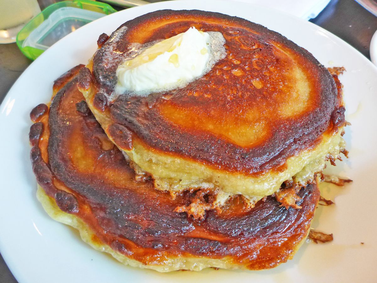 A stack of thick pancakes with butter melting on top.