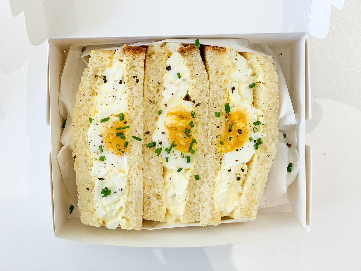 An egg salad sandwich covered in chives.
