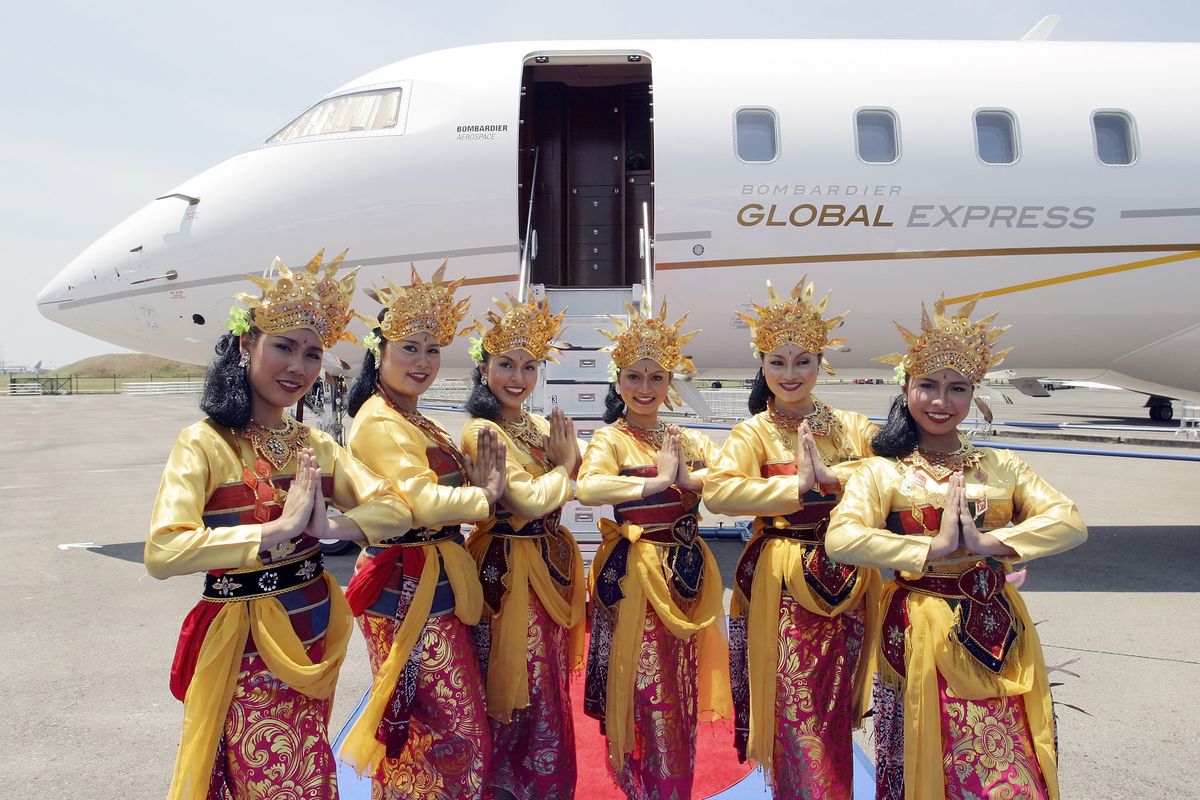 Balinese dancers pose in front of a Bombardier Global Expres
