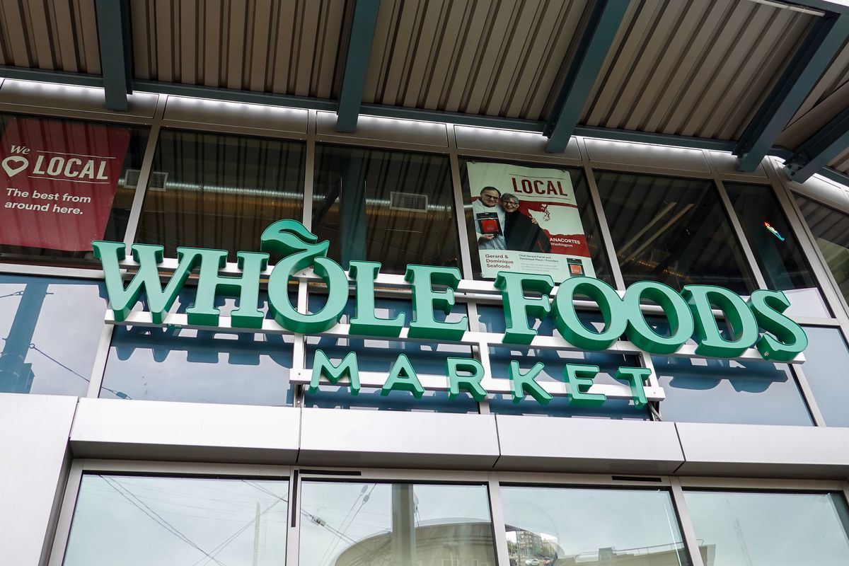 Exterior shot of a green sign reading Whole Foods Market on a glass building