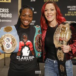 Claressa Shields and Cris Cyborg pose with their title belts at UFC 218 media day.
