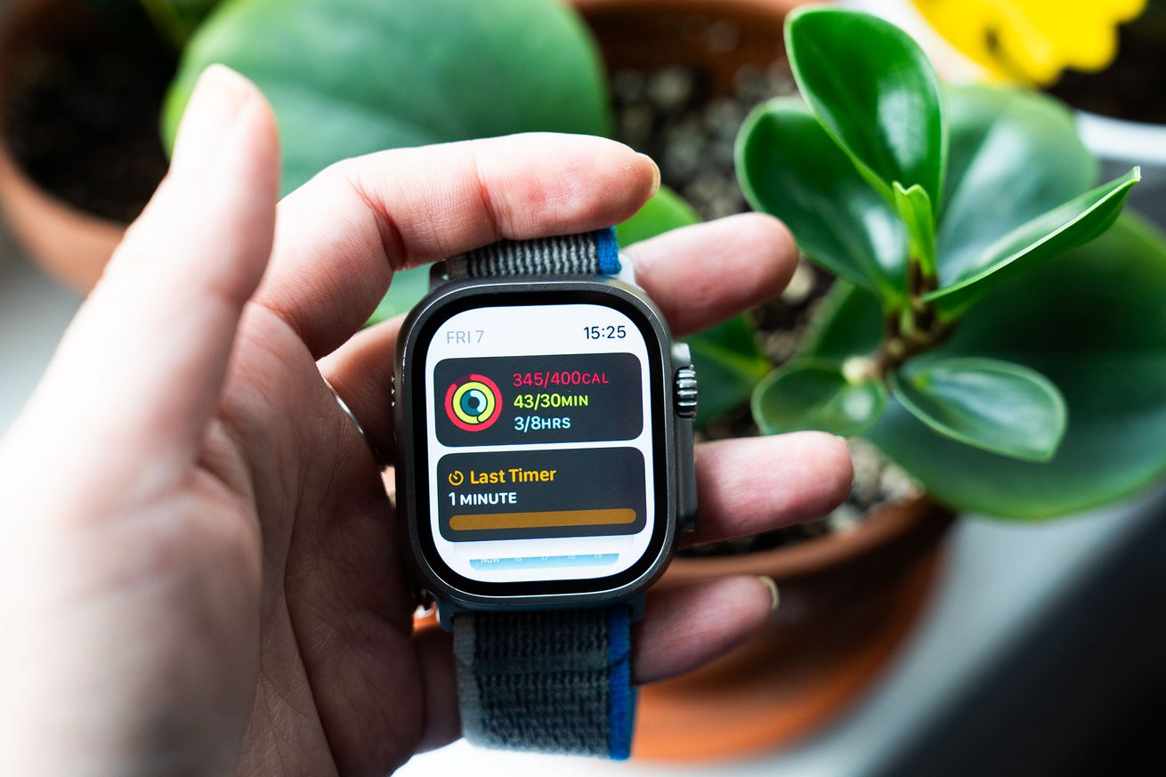 Person holding Apple Watch Ultra showing watchOS 10 widget stack