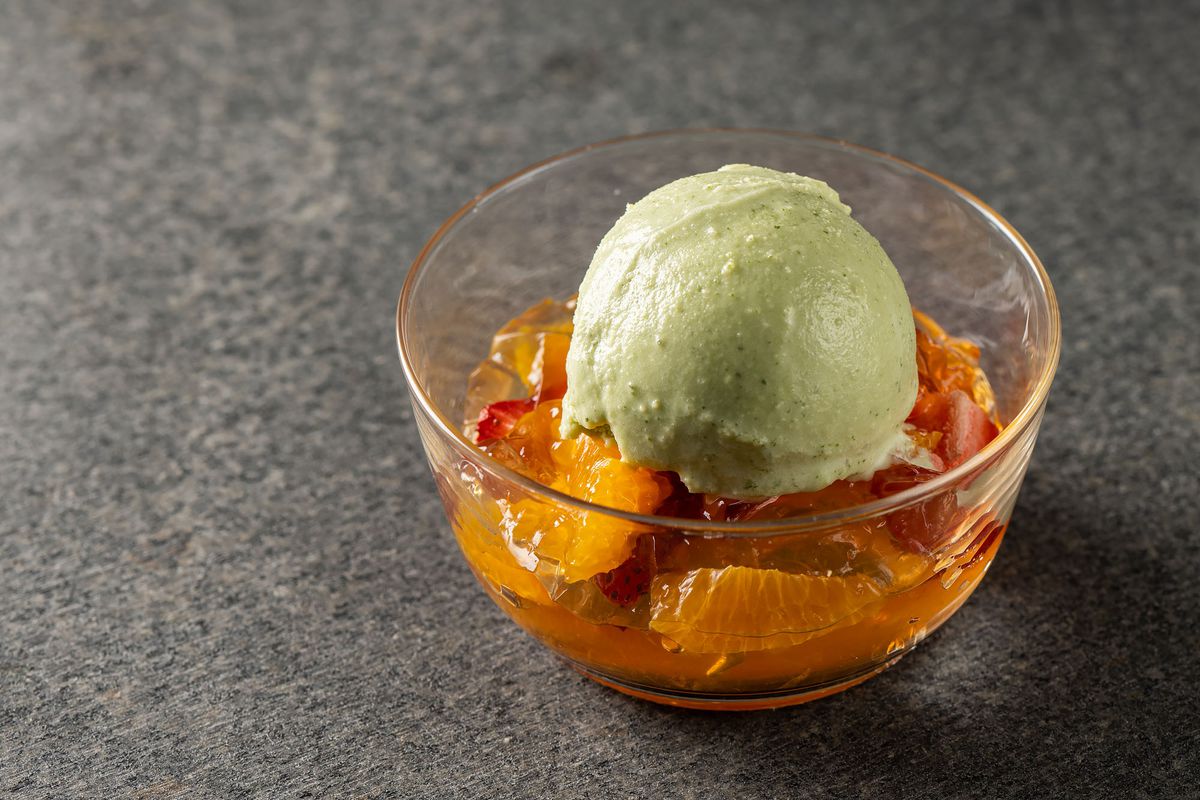 Candied orange fruit with an orb of ice cream on top.
