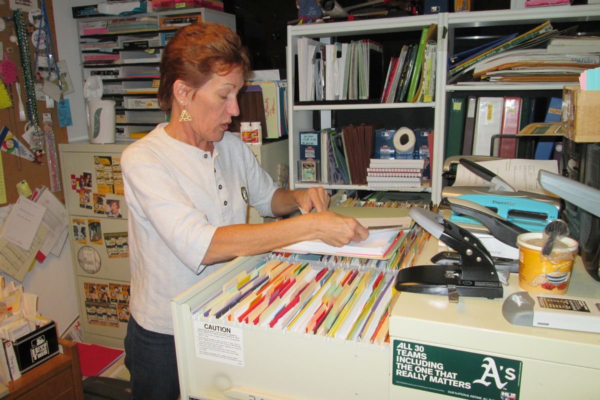 Pamela Pitts, A's Director of Baseball Administration, using MLB's information management technology, the file cabinet.