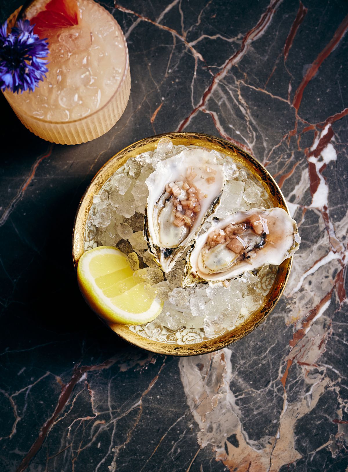 A pair of oysters with lemon over ice.