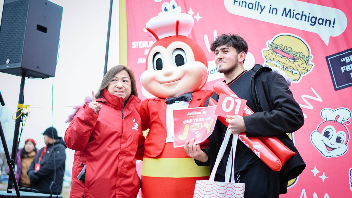 To the left, a woman with a red jacket, center, a red and yellow bee character wearing a red jacket, bow tie, chef hat, and a male with short hair and black jacket holding a noise maker.