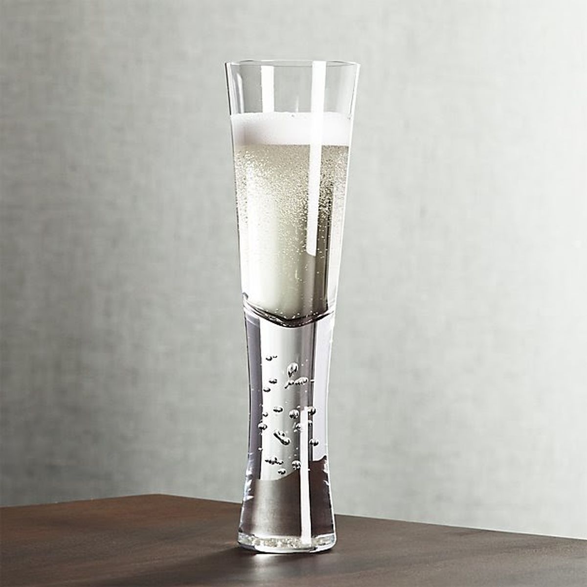 A champagne glass with a wide base on a brown table