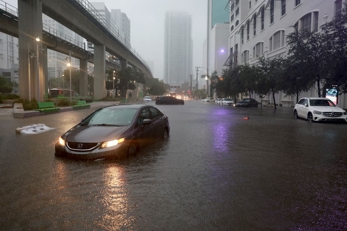 Cars sit in a flooded street caused by a deluge of rain from a tropical rain storm passing through Miami, Florida.