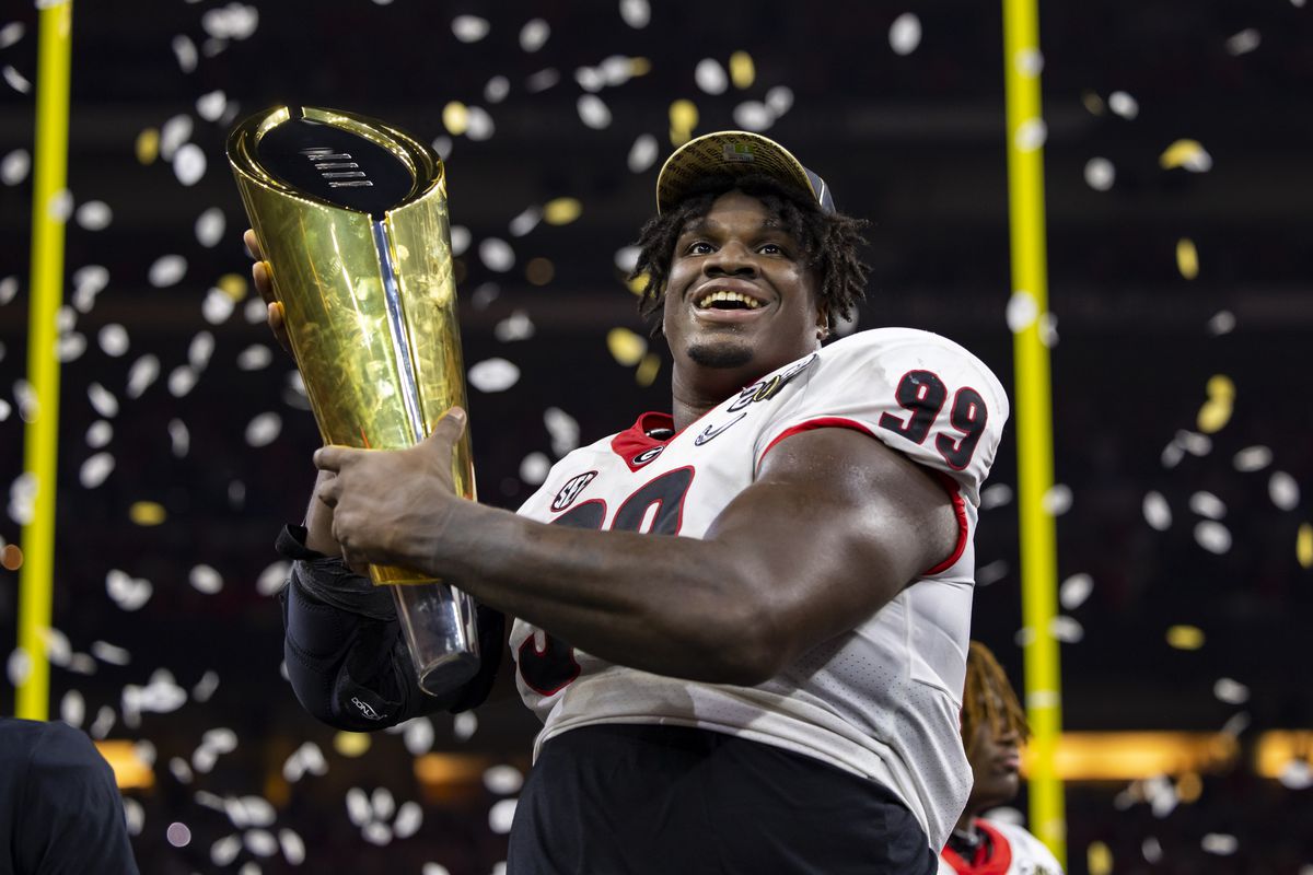 Georgia Bulldogs defensive lineman Jordan Davis (99) celebrates with the championship trophy after defeating the Alabama Crimson Tide in the 2022 CFP college football national championship game at Lucas Oil Stadium.