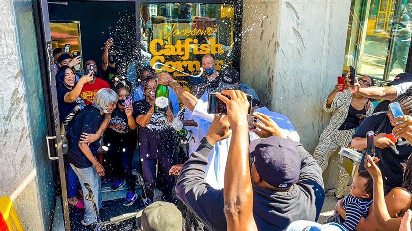 A crowd celebrates with sprays of champagne outside Jackson’s Catfish Corner on Jackson Street in the Central District.