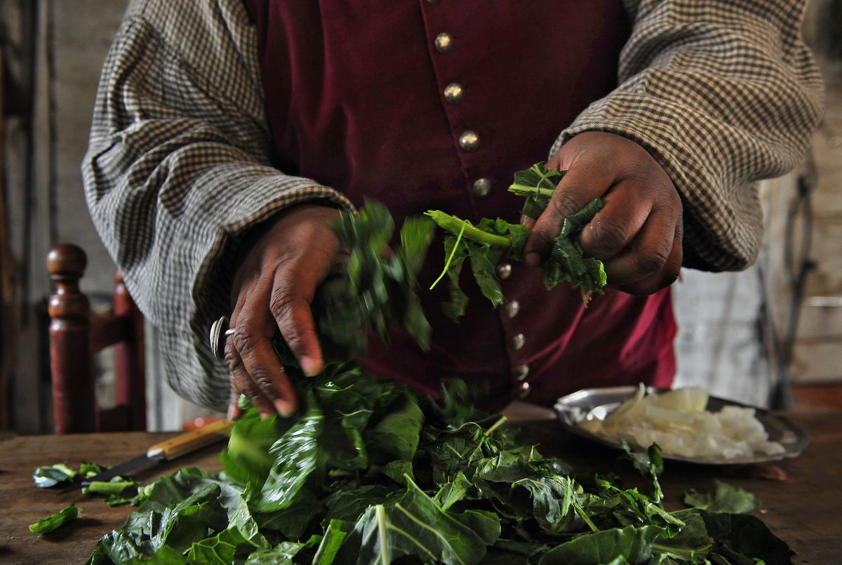 Closeup of chef Michael Twitty’s hands, which are tossing greens