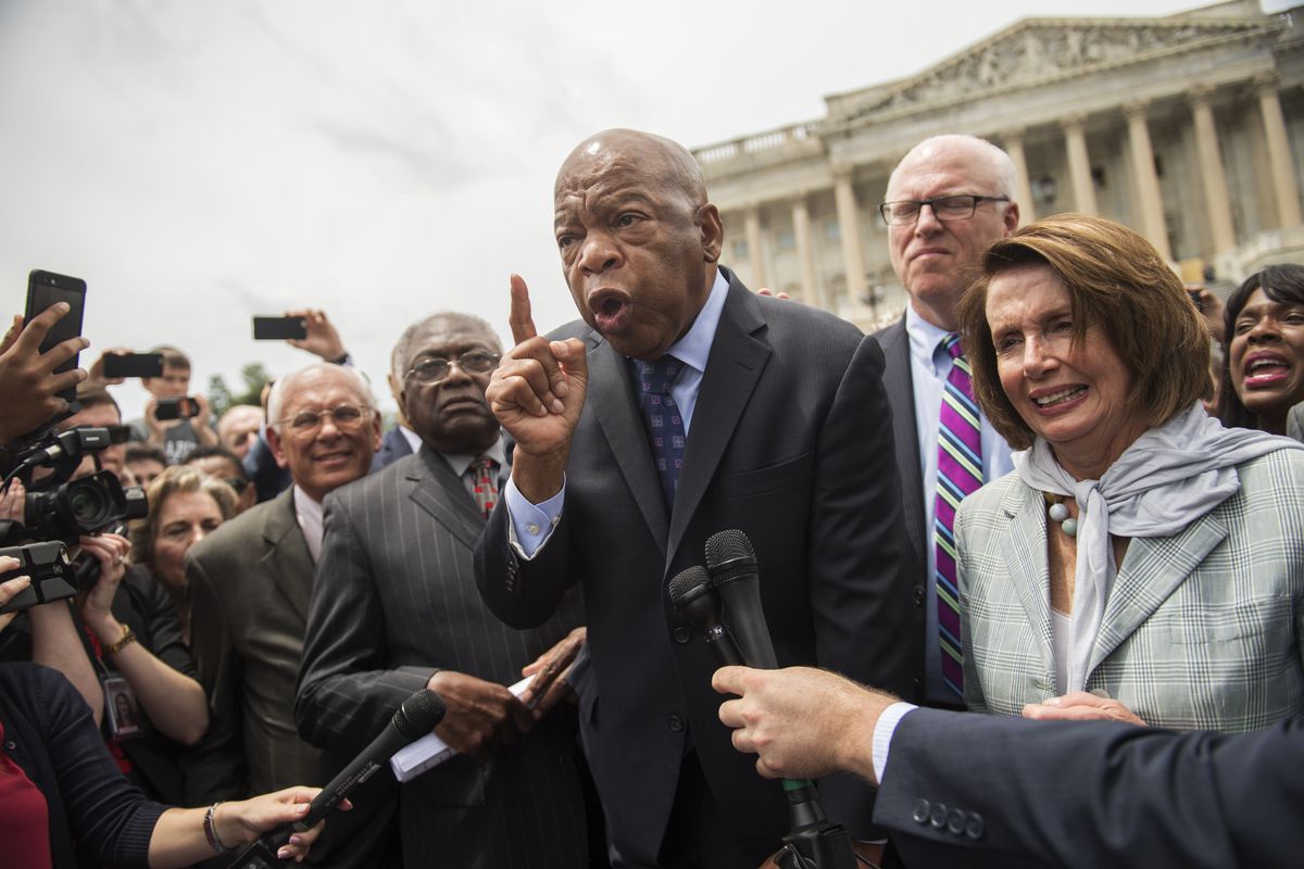 Lewis appears angry, his face strained as he speaks surrounded by Democratic leaders, including Nancy Pelosi and James Clyburn.