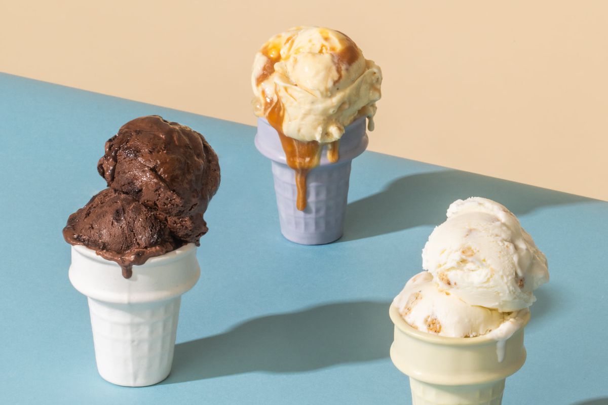 Three cake ice cream cones on a blue table (chocolate, caramel, and everything bagle ice cream)