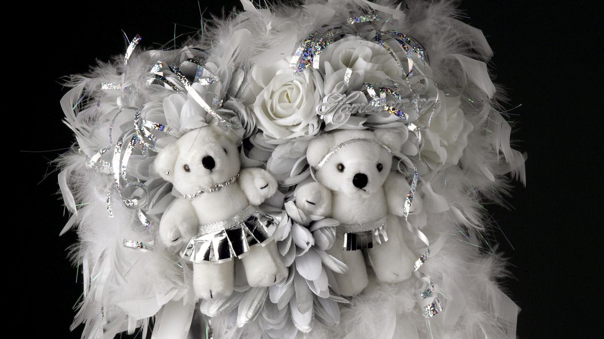 A silver and white homecoming mum with stuffed bears on it. 