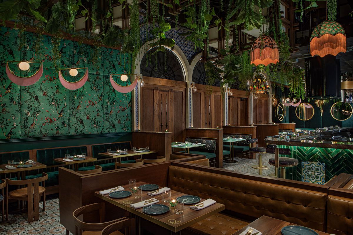 Wooden booths and tan leather reveal a colorful, green dinnertime dining room at LA’s new Que Barbaro.